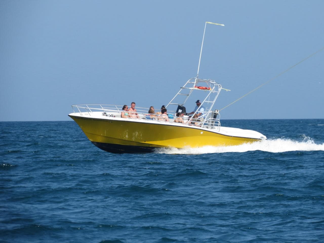 The yellow parasail boat running offshore with a full load of guests and the tow line paying out.