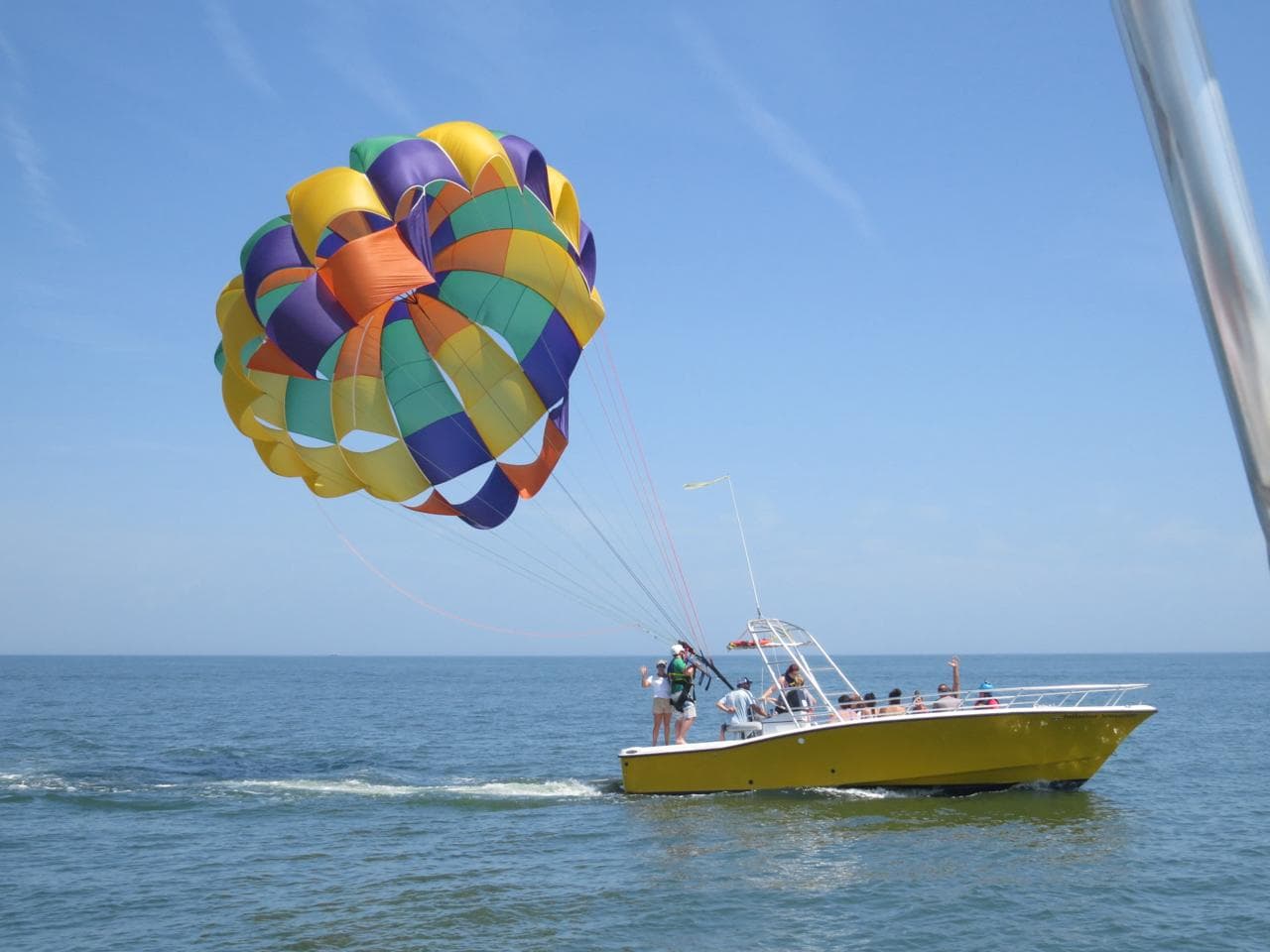 A rainbow parasail canopy filling with air alongside the boat as the crew prepares to launch.
