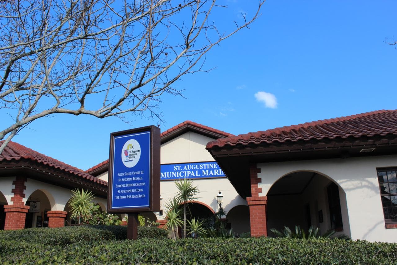 The St. Augustine Municipal Marina building, its entrance sign listing St. Augustine Parasail among the operators on the dock.